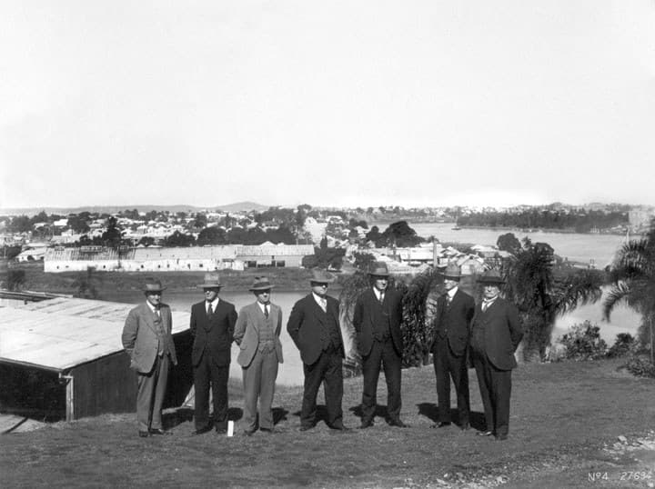 Officials inspecting a construction site in Brisbane in 1934, gathered around plans at the edge of the works.